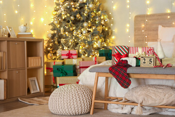 Gift boxes, Christmas sock, calendar and candy canes on bench in stylish bedroom