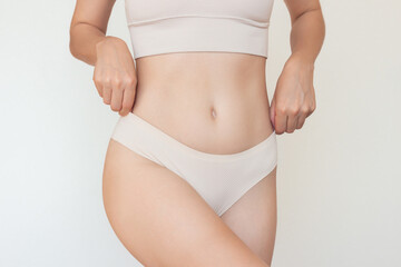 A shoot of a young slim Caucasian woman in beige underwear posing for the camera. Beauty, sports,...