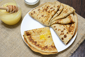 a plate of pancakes with a cup of syrup next to it 