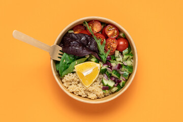 Quinoa with tomatoes arugula salad in recyclable food container. Healthy food on orange background top view. Eco food delivery concept