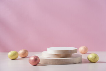 Wooden round podium with decorative easter eggs on pink background