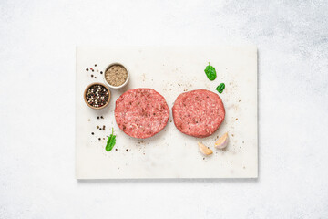 Raw piece of steakburger on marble board with spices. Marbled beef for making burger