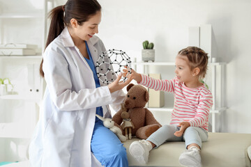 Female pediatrician and cute little girl with molecular model in clinic