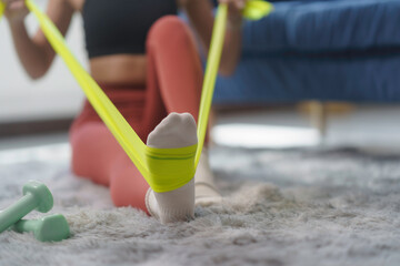 Close up of a woman's foot engaging with a resistance band during an invigorating home workout,...