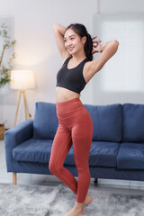 Obraz premium Fit asian woman wearing sportswear, tying her hair and preparing for exercising in the living room