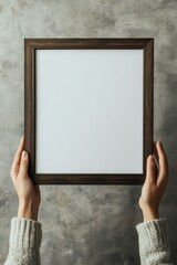 A hand holding an empty wooden picture frame, ready for custom artwork or photo, in a cozy home setting with soft tones and minimalist decor.






