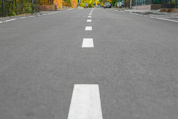 Asphalt surface with white dividing strip in the middle with perspective running along a street...