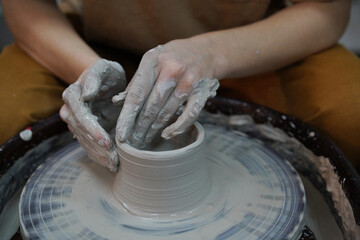 Woman working on the potter's wheel. Hands of young master of ceramics working