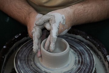 Hands of a potter on a pottery. Pottery workshop in subdued soft light