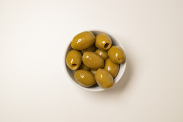 Whole green olives in a bowl on black background. Top view, close-up. High quality photo