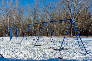 Swings in winter playground with snow