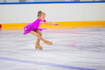 Full length portrait of little girl doing figure skating on indoor rink during performance, copy...