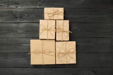 Gift boxes in Christmas tree shape on wooden background, top view