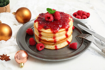 Plate of sweet pancakes with raspberry jam and Christmas balls on white background