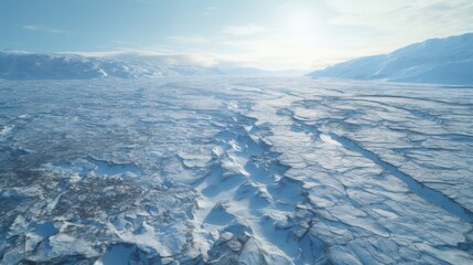 Stunning aerial view of a vast, icy landscape under a bright blue sky. Frozen textures stretch far and wide as mountain peaks rise in the distance, creating a breathtaking winter scene.