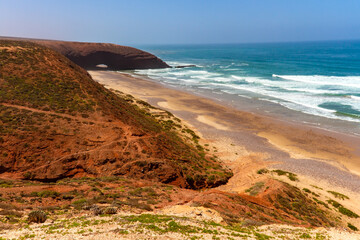 Red rocks with a natural arch on the coast of the Atlantic Ocean. Legzira beach ( or Lagzira, or Gzira). Sidi Ifni, Morocco, Africa