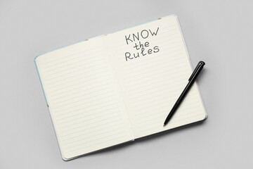 Notebook with text KNOW THE RULES on light background