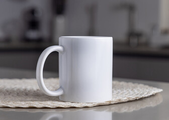 Closeup of  white blank coffee mug on grey kitchen table over blured kitchen interior, mockup