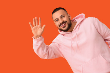 Young man waving hand on orange background. Rules concept