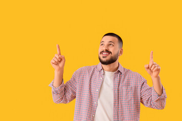 Young man pointing at something on yellow background. Rules concept