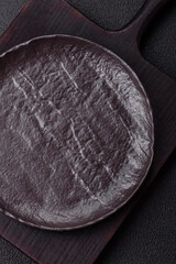 Empty black ceramic plate on a dark concrete background