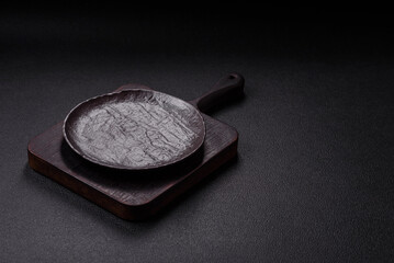 Empty black ceramic plate on a dark concrete background