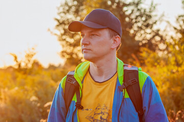 Young man in a colorful outfit gazing into the distance during a sunset in a field.