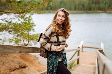 Relaxed woman tourist enjoying nature, breathing fresh air on the lake. Solitude with nature. Active lifestyle.