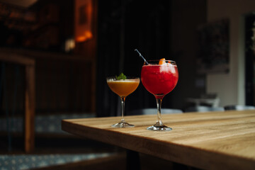 Two colorful summer cocktails in glasses on wooden table. Assortment of fresh summer drinks. Red sangria cocktails, orange punch cocktail. High quality photo