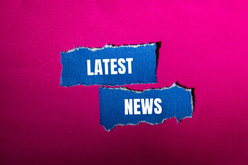 Latest news message written on ripped torn blue paper pieces with pink background. Conceptual latest news symbol. Copy space.