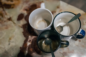 three empty mugs with spoons on table
