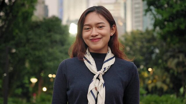 Smiling young Asian woman wearing an elegant scarf in the city park