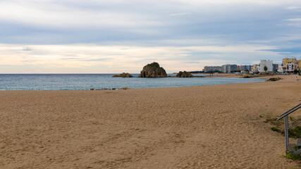 Vista desde el puerto de Blanes hacia la Punta Sa Palomera, con playa, mar y edificios al fondo.