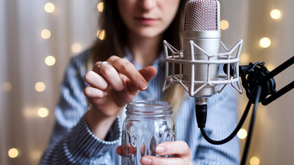 Woman ASMRtist tapping a glass jar, soothing sounds. Microphone placed near to jar, blurred background, close-up shot photo generative ai