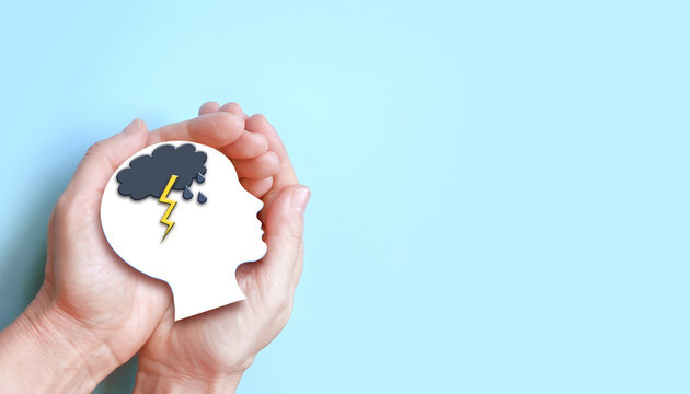 Hands holding paper brain with storm, rain, cloud, mental health, self care concept.