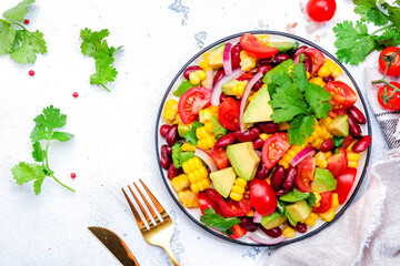 Corn salad with red beans, avocado, tomatoes, onion and cilantro. White background, top view