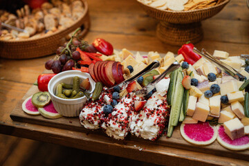 beautiful spread of goat cheese, vegetables, charcuterie, fruit on wooden serving board at holiday party 