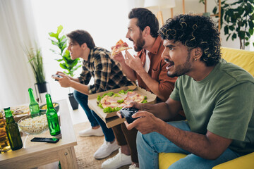 Photo of company three friends eat pizza play video game hang out weekend modern interior apartment indoors