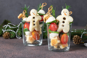 Canapes with cherry tomatoes, mozzarella cheese, spinach and snowmen puff pastry in two glass