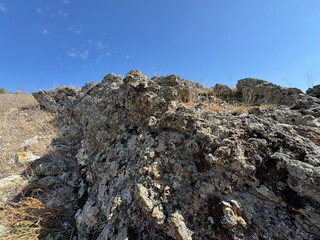 Mountain rock moss and blue sky texture close-up background. Gray, black dark brown stone rock granite basalt texture background. Mountains surface. Close-up. Mossy rock and sky texture.
