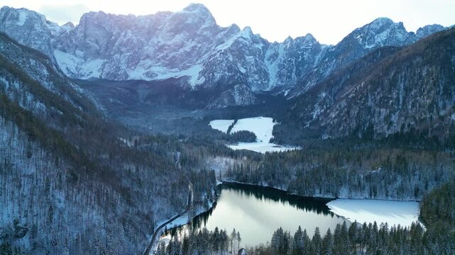 Lago di Fusine and Lago di Fusine Superiore, nestled in the Italian Alps, reveal their enchanting winter beauty when viewed from the air. Surrounded by snow-capped peaks and dense forests