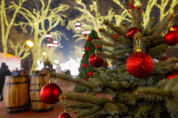 Festive Christmas tree with red ornaments in a holiday market setting.