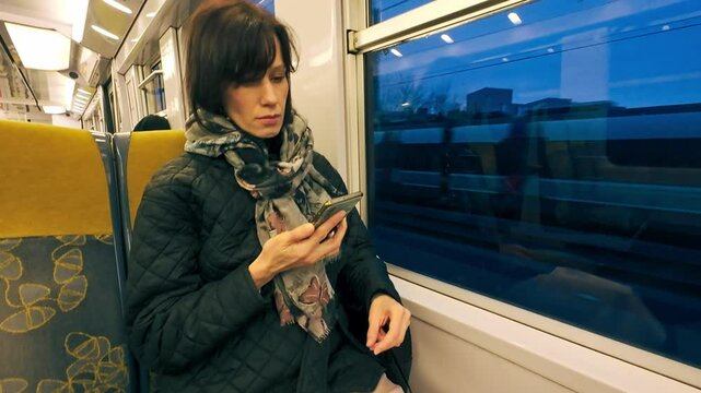 Woman at metro train in Paris, looking to mobile phone in early morning. Public transport in Paris, France
