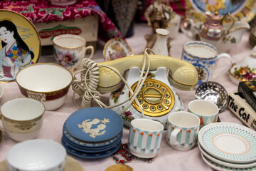 London, UK. November 13, 2024. Disk porcelain or ceramic phone, cups, and saucers at a flea market...