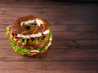 Turkish bagel sandwich, studio image of delicious Turkish bagel sandwich on wooden table dark brown background with copy space workspace area. Menu design concept or advertisement idea photo. © Designerant