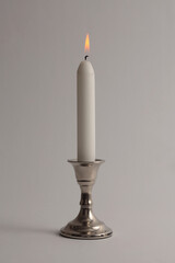 Burning candles in silver candlestick. Evening, night Light and shadow gray neutral background. Minimalist still life.