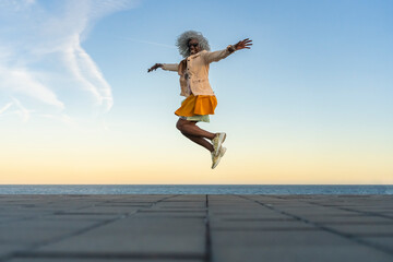 Stylish, smiling afro lady with grey afro hairstyle jumping