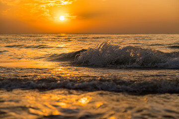 Aufnahme einer brechenden Welle im Sonnenuntergang am Meer.