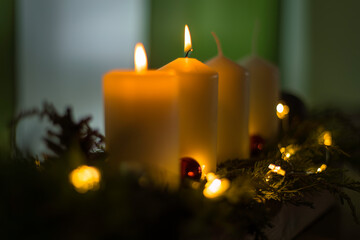 Aufnahme eines Adventskranzes mit zwei brennenden Kerzen und Weihnachtsdeko.