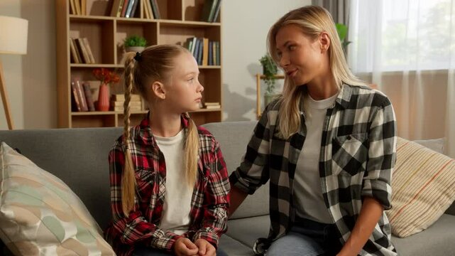 Family argument. Offended upset little Caucasian girl child daughter cross arms ignore mother parent woman at home caring guilty mom female touch schoolgirl kid speaking talk apologize quarrel trouble